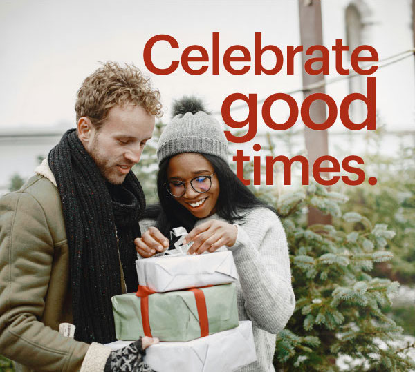 Couple holding gifts with trees in the background.