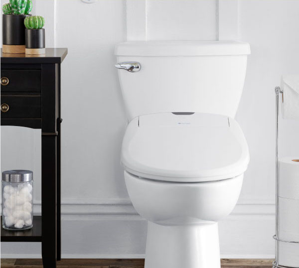 Modern bathroom with the Sutro Integrated Smart Bidet Toilet, open lid, dark stone tiles, glass-partitioned tub, floating vanity, and ambient lighting.