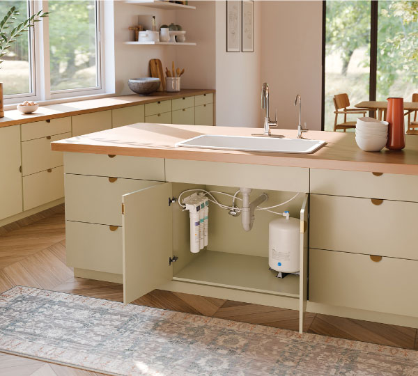Capella Reverse Osmosis Water Filtration System installed under a modern kitchen sink with green cabinets and wood countertops, highlighting sleek, compact design.