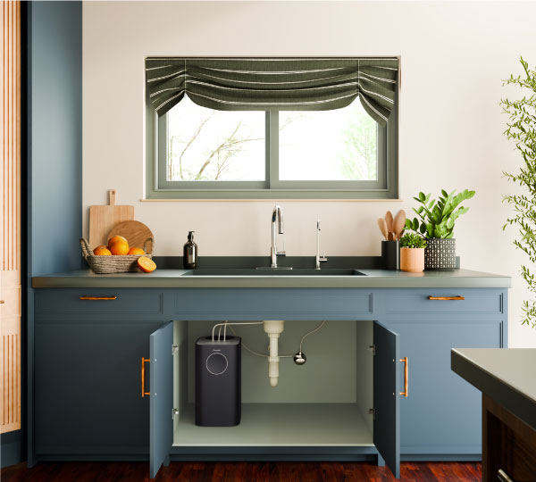 Capella Reverse Osmosis Water Filtration System installed under a modern kitchen sink with green cabinets and wood countertops, highlighting sleek, compact design.