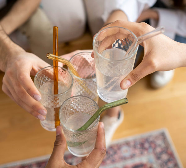Friends clinking glasses of fresh water with reusable straws, highlighting clean, refreshing drinking water and the everyday enjoyment of pure, filtered water at home.