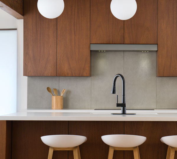 Jema Single-Handle Pull-Down Kitchen Faucet in matte black shown against a dark background, highlighting its curved spout and smooth water stream for a sleek, modern look.