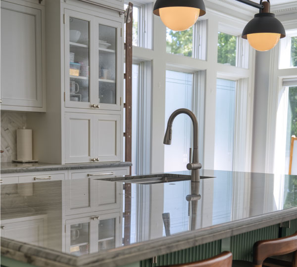 Bright modern kitchen with large windows and island sink featuring Jema Single-Handle Pull-Down Kitchen Faucet in brushed finish beneath stylish pendant lighting.