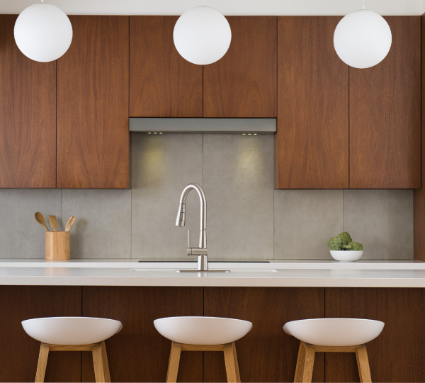 Capella Reverse Osmosis Water Filtration System installed under a modern kitchen sink with green cabinets and wood...